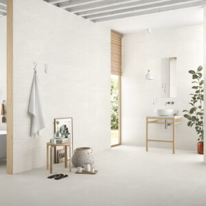 Baño exposición con azulejos blancos, suelo cerámico, bañera, lavabo y estantería de madera