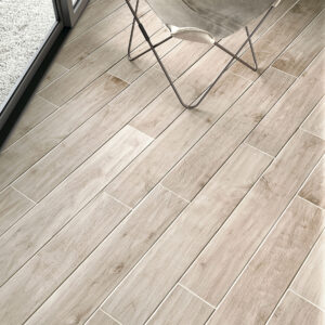 Baldosa cerámica efecto madera clara con silla mariposa junto a ventanal