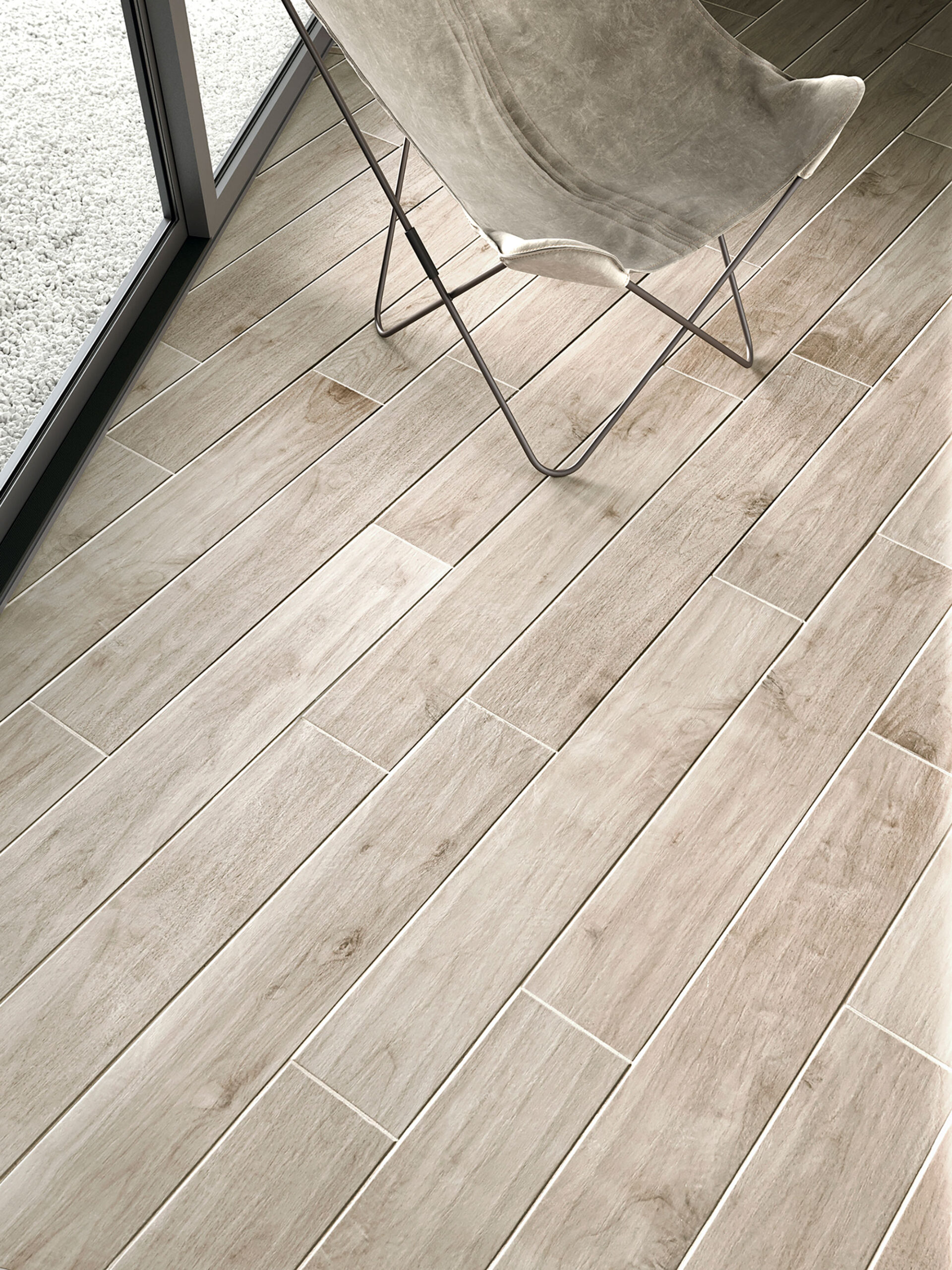 Baldosa cerámica efecto madera clara con silla mariposa junto a ventanal