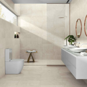 Baño minimalista con azulejos beige, lavabo doble, espejos redondos y ducha abierta