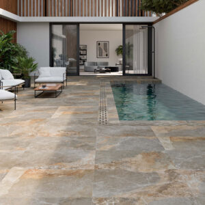 Patio moderno con grandes losas cerámicas efecto piedra, zona de estar y piscina estrecha.