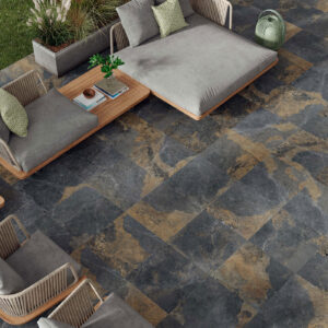 Terraza con pavimento cerámico oscuro veteado, mobiliario lounge de madera y cojines.