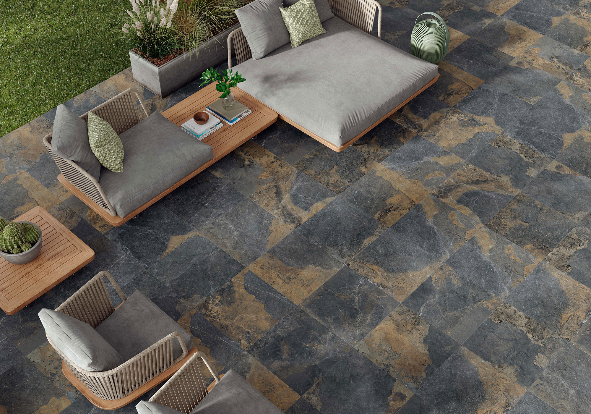 Terraza con pavimento cerámico oscuro veteado, mobiliario lounge de madera y cojines.