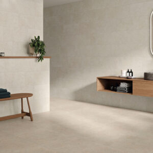 Escena de baño con pavimento y revestimiento cerámico beige, mueble flotante y banco de madera