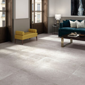 Salón moderno con suelo de grandes losas cerámicas gris claro, sofá verde y banco amarillo