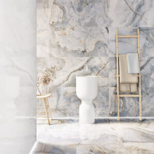 AMB_Eunoia_Blue_60x120_MQ Baño con azulejos efecto mármol en paredes y suelo, lavabo blanco y escalera toallero