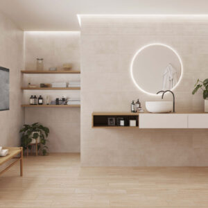 AMB_KTL_COLUMBIA+LINES_30x60_HASPE-20,5x61,5_BAJA Baño showroom con azulejos y pavimento cerámico beige, lavabo y espejo circular iluminado