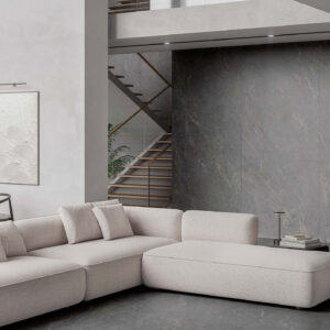 Salón showroom con sofá modular beige sobre pavimento y revestimiento cerámico gris