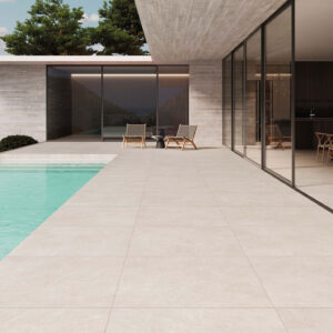 Terraza con grandes losas cerámicas junto a piscina y salón acristalado