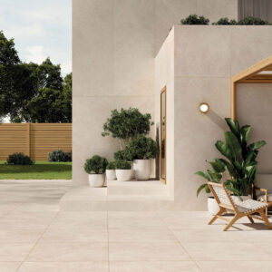 Terraza exterior con pavimento y revestimiento cerámico crema, macetas y pérgola de madera