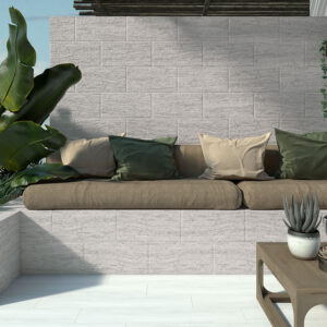 Muestra de revestimiento cerámico texturado, banco empotrado con cojines y suculentas