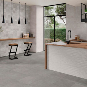 Showroom de azulejos: suelo y pared cerámica gris, isla de madera y dos taburetes