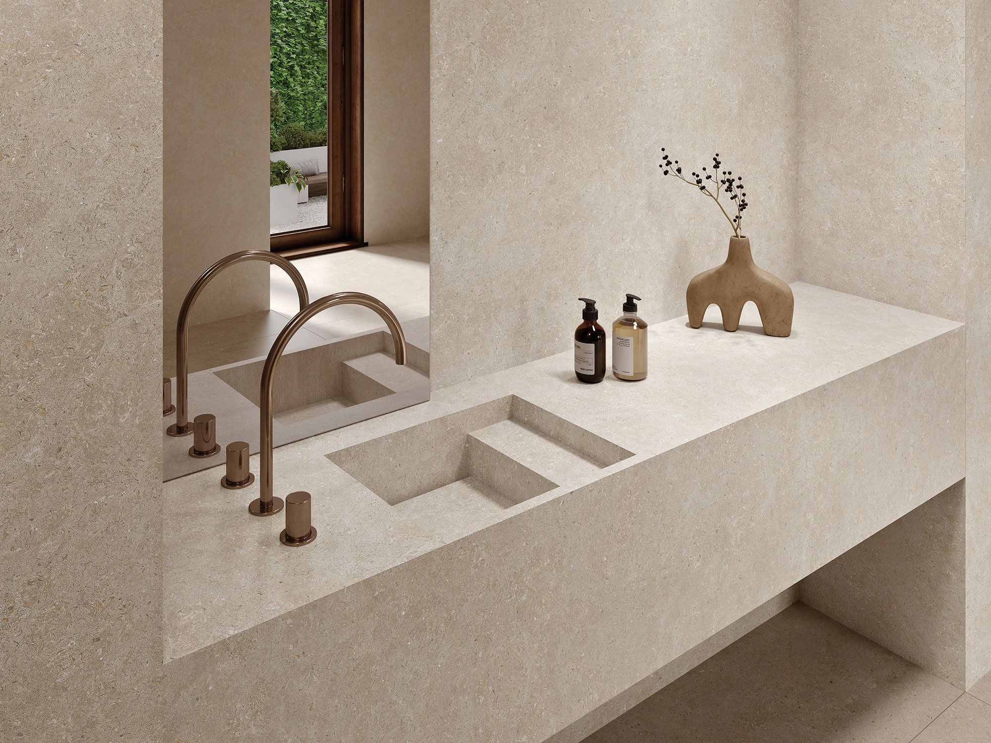 Lavabo integrado y encimera de gres beige con grifo bronce, dispensadores y jarrón