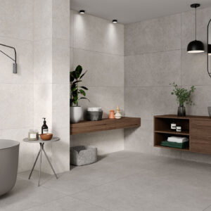 Baño minimalista con grandes azulejos grises, bañera exenta y mueble flotante de madera.