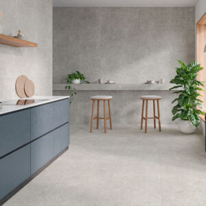 Showroom de azulejos: cocina con pavimento y revestimiento cerámico gris, muebles azules y plantas.