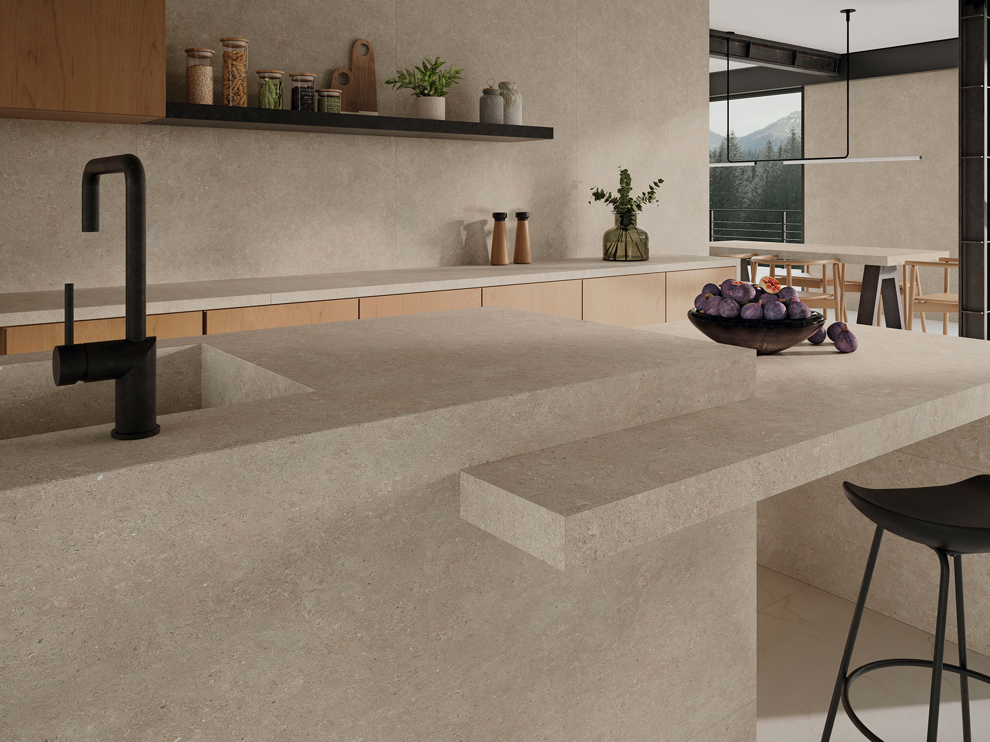 Cocina moderna con isla y revestimiento cerámico beige, grifo negro y cuenco de higos.
