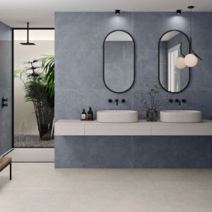 Baño expositivo de azulejos grisados, doble lavabo en encimera flotante y ducha con planta