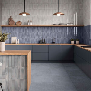 Cocina exposición con azulejos verticales azul y gris, encimeras madera y suelo cerámico.