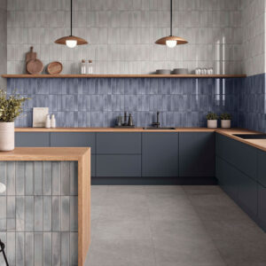 Cocina de exposición con azulejos verticales azules, encimeras de madera y suelo cerámico.