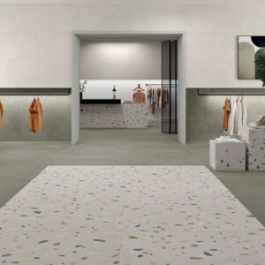 Tienda de azulejos con suelo y paredes neutras, franja central tipo terrazo y exposiciones.