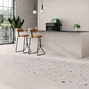 Cocina showroom con isla y taburetes sobre pavimento cerámico tipo terrazo claro