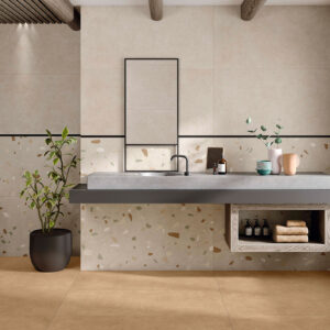 Baño de tienda con azulejos beige, cenefa negra, suelo claro y lavabo flotante de hormigón