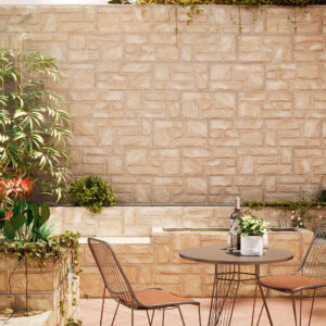 Terraza con revestimiento cerámico efecto piedra, mesa redonda, dos sillas y plantas