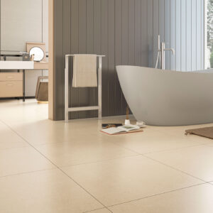 Baño de exposición con suelo cerámico beige en grandes losas, bañera exenta gris y tocador