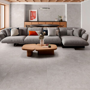 Salón de exposición con pavimento cerámico gris, sofá modular y mesa de madera