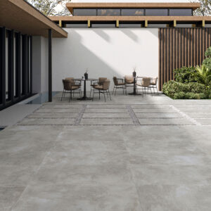 ELEMENTI-GREY-60X120_20MM Patio exterior con grandes losas cerámicas grises, zona de mesas y jardín
