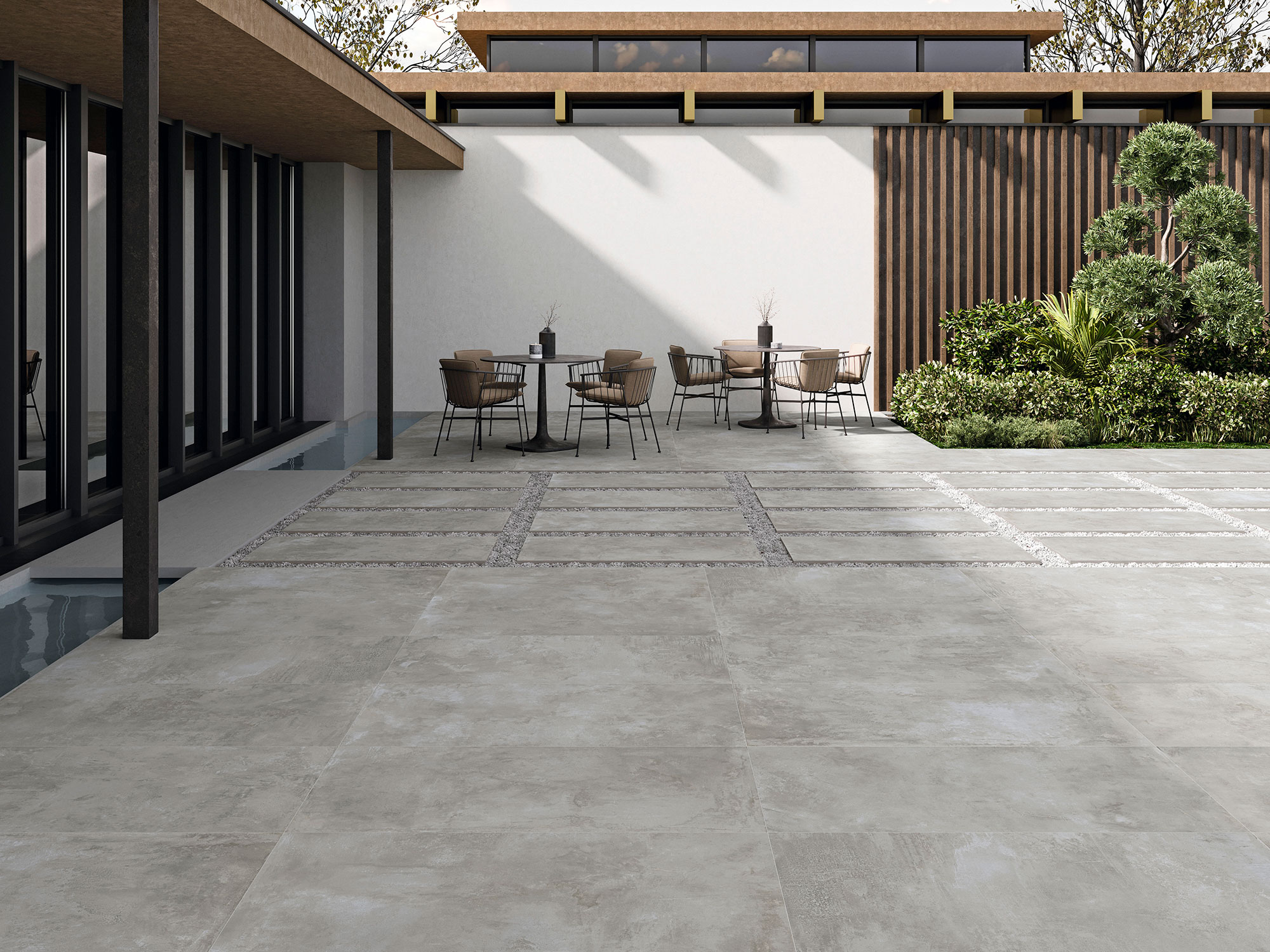 ELEMENTI-GREY-60X120_20MM Patio exterior con grandes losas cerámicas grises, zona de mesas y jardín
