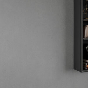 Revestimiento cerámico gris de gran formato junto a estantería mural negra con libros