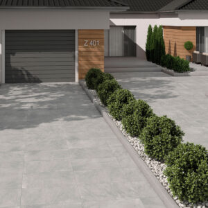 Porche y entrada con pavimento cerámico gris efecto piedra, setos y garaje