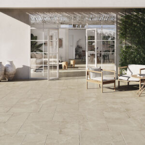 Pavimento cerámico beige en patio con puertas acristaladas, plantas y mobiliario.