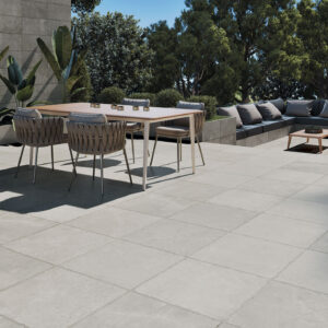 Terraza con pavimento cerámico gris, mesa de comedor y rincón de sofás