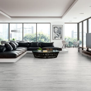 Salón showroom con sofá negro y pavimento cerámico efecto madera gris