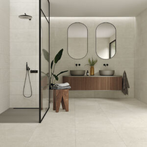 Baño moderno con azulejos beige, ducha de vidrio, mueble flotante de madera y doble lavabo