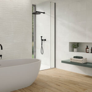 Baño de exposición con bañera exenta, azulejos cerámicos texturizados en ondas y suelo imitación madera