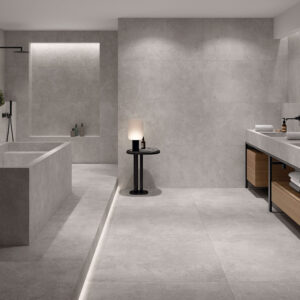 Baño expositor con grandes azulejos cerámicos grises, bañera integrada y doble lavabo.