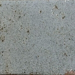 Azulejo rectangular gris claro esmaltado con motas oscuras y canto marrón