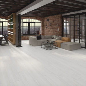 Showroom con pavimento cerámico blanco efecto madera en loft con muro de ladrillo.