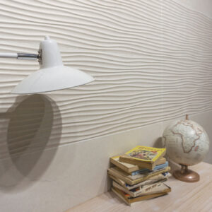 Detalle de revestimiento cerámico ondulado blanco con lámpara, libros y globo