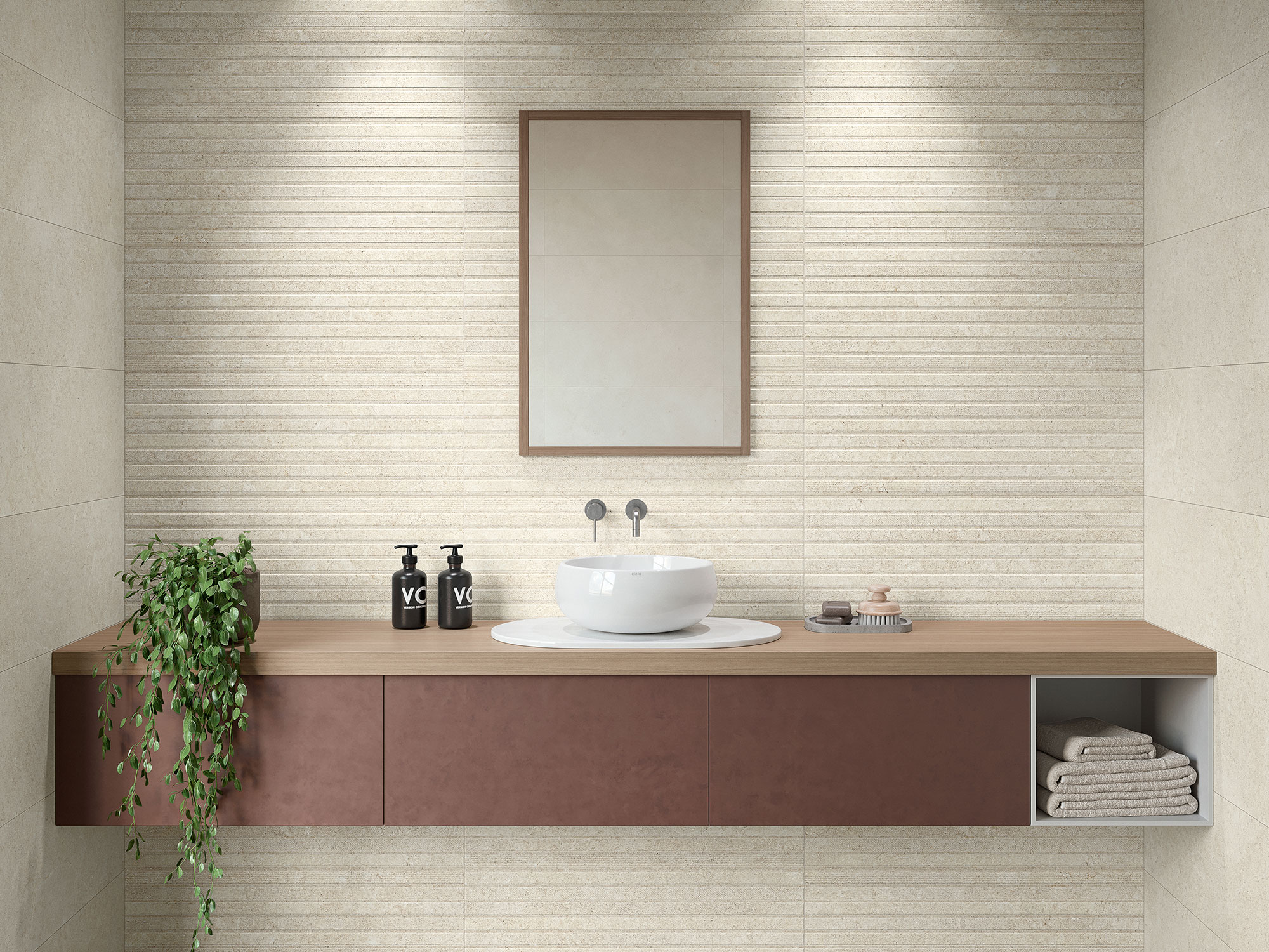 Lavabo sobre encimera de madera con revestimiento cerámico beige estriado, espejo y toallas.
