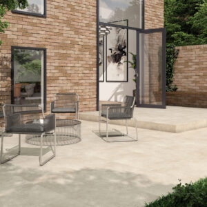 Terraza con azulejos cerámicos claros, pared de ladrillo y mobiliario exterior minimalista