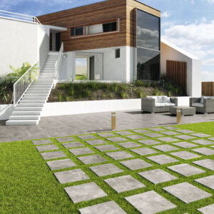 Casa moderna con terraza y camino de losetas cerámicas sobre césped y mobiliario exterior