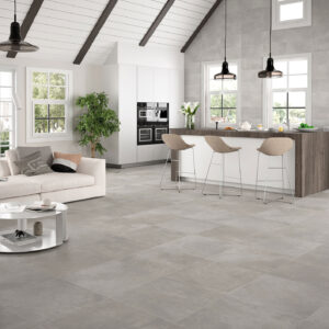 Salón-cocina abierto con amplias baldosas cerámicas grises, isla y ventanales.