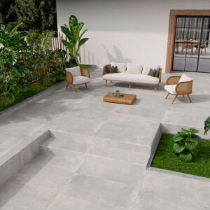 SONDER-GREY-60X120-PIEZAS-ESPECIALES Terraza con pavimento cerámico gris, sofá y sillones de mimbre junto a jardineras