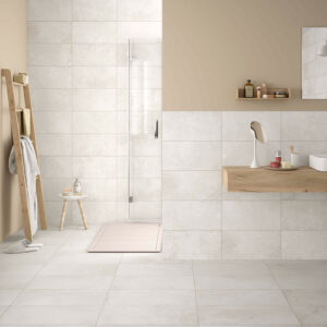 Baño de muestra con pavimento y revestimiento cerámicos claros, mueble flotante de madera