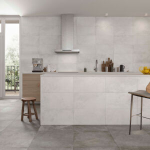 Cocina de exposición con pavimento y revestimiento cerámicos grises, isla central y taburetes