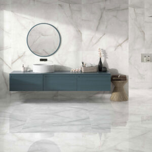 STN-AMB-BALTRA-PEARL-PULIDO_60X120 Showroom baño con azulejos efecto mármol, mueble azul flotante, espejo circular y mampara negra